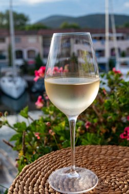 Yaz mevsiminde yerel soğuk beyaz şarabın tadına bakarken arka planda liman, Provence, Var, Fransa
