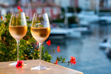 Tasting of local cold rose wine in summer on sunset with sail boats haven of Port grimaud on background, Provence, Var, France clipart