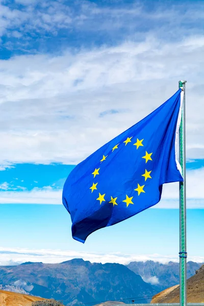 Blue with yellow stars Flag of Europe or European Union flag waving on mast in French Alpine mountains in sunny day