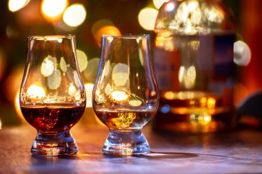 Edinburgh, İskoçya 'da arka planda parti ışıklarıyla birlikte barda servis edilen tek malt ve karışık viski bardakları