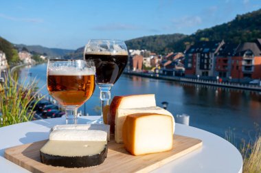 Bir bardak Belçika manastırı birası ve trapist birayla yapılan peynirleri tatmak ve Belçika, Dinant 'taki Maas nehri manzaralı güzel otlar.