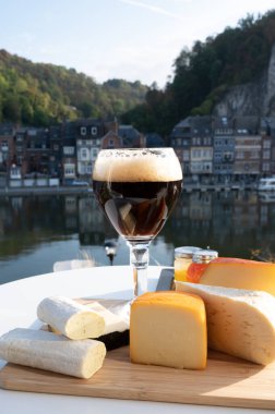 Bir bardak Belçika manastırı birası ve trapist birayla yapılan peynirleri tatmak ve Belçika, Dinant 'taki Maas nehri manzaralı güzel otlar.