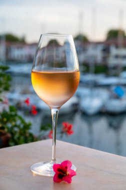 Yaz günbatımında yerel soğuk gül şarabının tadına bakmak arka planda liman, Provence, Var, Fransa