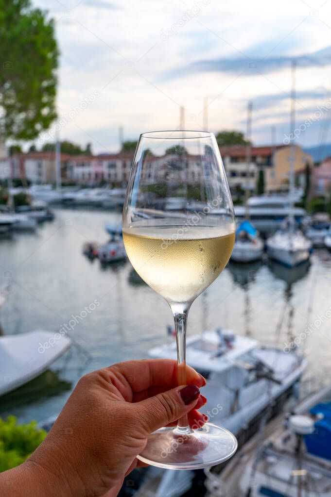Tasting of local cold white wine in summer with sail boats haven of Port grimaud on background, Provence, Var, France
