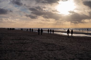 Hollanda 'da Zandvoort yakınlarında, Kuzey Denizi' nin geniş kumlu sahillerinde yürüyen kimliği belirsiz insanlar.