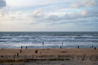 Hollanda 'da Zandvoort yakınlarında, Kuzey Denizi' nin geniş kumlu sahillerinde yürüyen kimliği belirsiz insanlar.