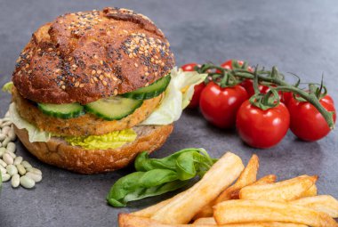 Sebze bazlı hamburgerle yapılan lezzetli vejetaryen öğle yemeği, tohumlu organik çörek ve taze sebze ve kızarmış patates.