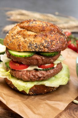 Bitki bazlı soya fasulyesi burgerinden yapılmış çift katlı vejetaryen hamburgeri, tohumlu organik çörekler ve taze sebzelerle lezzetli vejetaryen yemeği hazırlıyorum.