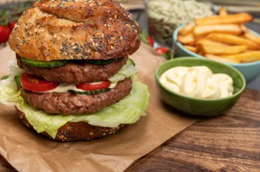 Bitki bazlı soya fasulyesi burgerinden yapılmış çift katlı vejetaryen hamburger, tohumlu organik çörek ve taze sebze ve kızarmış patates.