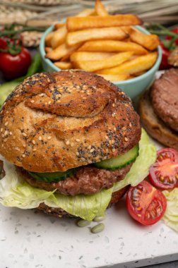 Bitki bazlı soya fasulyeli hamburgerle lezzetli vejetaryen yemeği, tohumlu organik çörek ve taze sebze ve kızarmış patates yapıyorum.