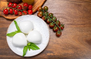 Peynir koleksiyonu, beyaz İtalyan peynirli mozzarella topları, kırmızı vişneli domates ve taze fesleğen yapraklarıyla servis ediliyor.