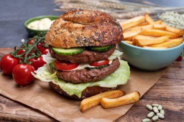 Bitki bazlı soya fasulyesi burgerinden yapılmış çift katlı vejetaryen hamburger, tohumlu organik çörek ve taze sebze ve kızarmış patates.