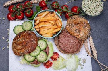 Bitki bazlı soya fasulyeli hamburgerle lezzetli vejetaryen yemeği, tohumlu organik çörek ve taze sebze ve kızarmış patates yapıyorum.