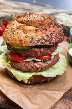 Bitki bazlı soya fasulyesi burgerinden yapılmış çift katlı vejetaryen hamburgeri, tohumlu organik çörekler ve taze sebzelerle lezzetli vejetaryen yemeği hazırlıyorum.