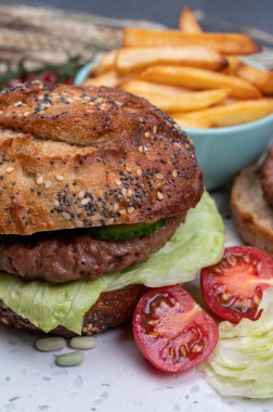 Bitki bazlı soya fasulyeli hamburgerle lezzetli vejetaryen yemeği, tohumlu organik çörek ve taze sebze ve kızarmış patates yapıyorum.