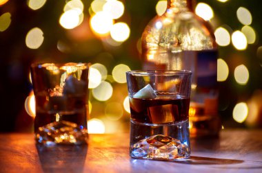 Edinburgh, İskoçya 'da arka planda parti ışıklarıyla birlikte barda servis edilen tek malt ve karışık viski bardakları