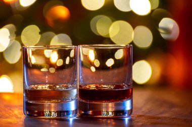 Edinburgh, İskoçya 'da arka planda parti ışıklarıyla birlikte barda servis edilen tek malt ve karışık viski bardakları