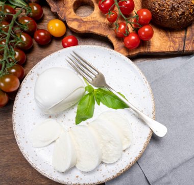 Peynir koleksiyonu, beyaz İtalyan peyniri mozzarellası yemek, kırmızı vişneli domates ve taze fesleğen yapraklarıyla servis edilmek.