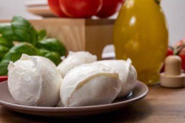 Peynir koleksiyonu, küçük beyaz mozzarella peynir topları kırmızı domates ve taze yeşil fesleğenle servis ediliyor.