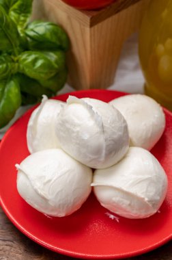 Peynir koleksiyonu, küçük beyaz mozzarella peynir topları kırmızı domates ve taze yeşil fesleğenle servis ediliyor.