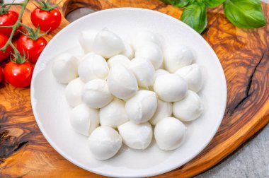 İtalyan üç renkli, küçük toplar taze İtalyan mozzarella peyniri olgun kırmızı kiraz domatesleri ve taze yeşil fesleğen otu Caprese salatası yapmaya hazır, kapatın.