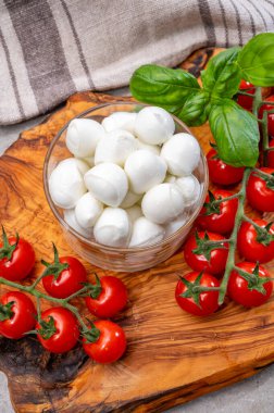 İtalyan üç renkli, küçük toplar taze İtalyan mozzarella peyniri olgun kırmızı kiraz domatesleri ve taze yeşil fesleğen otu Caprese salatası yapmaya hazır, kapatın.