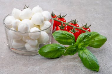 İtalyan üç renkli, küçük toplar taze İtalyan mozzarella peyniri olgun kırmızı kiraz domatesleri ve taze yeşil fesleğen otu Caprese salatası yapmaya hazır, kapatın.