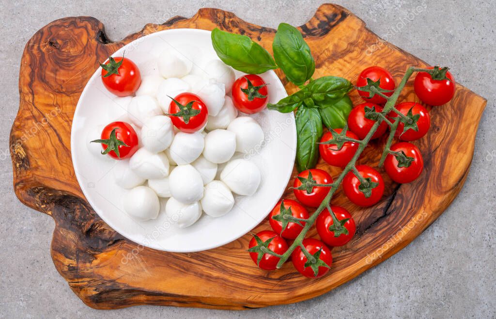Italian tricolore, small balls of fresh white soft Italian mozzarella cheese, ripe red cherry tomatoes and fresh green basil herb, ready for making caprese salad, close up