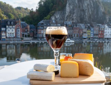 Bir bardak Belçika manastırı birası ve trapist birayla yapılan peynirleri tatmak ve Belçika, Dinant 'taki Maas nehri manzaralı güzel otlar.