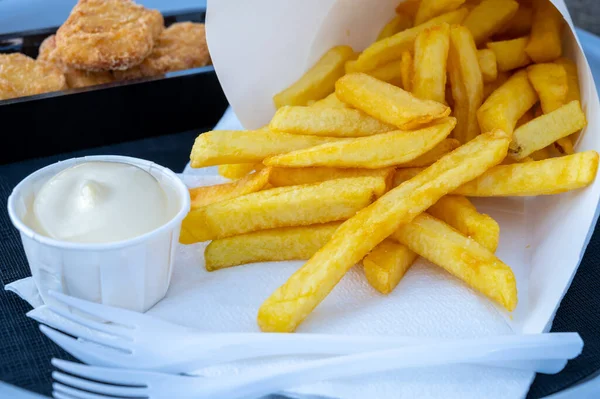 Eatiog of street or take away food fresh baked french fried potatoes chips in paper cone