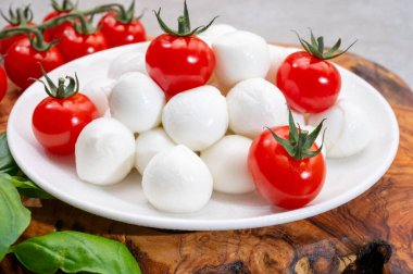 İtalyan üç renkli, küçük toplar taze İtalyan mozzarella peyniri olgun kırmızı kiraz domatesleri ve taze yeşil fesleğen otu Caprese salatası yapmaya hazır, kapatın.