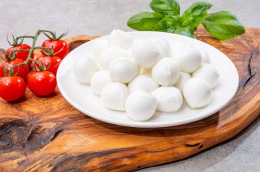 İtalyan üç renkli, küçük toplar taze İtalyan mozzarella peyniri olgun kırmızı kiraz domatesleri ve taze yeşil fesleğen otu Caprese salatası yapmaya hazır, kapatın.