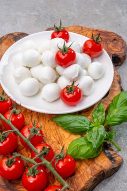 İtalyan üç renkli, küçük toplar taze İtalyan mozzarella peyniri olgun kırmızı kiraz domatesleri ve taze yeşil fesleğen otu Caprese salatası yapmaya hazır, kapatın.