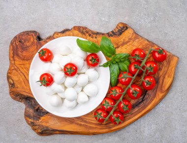 İtalyan üç renkli, küçük toplar taze İtalyan mozzarella peyniri olgun kırmızı kiraz domatesleri ve taze yeşil fesleğen otu Caprese salatası yapmaya hazır, kapatın.