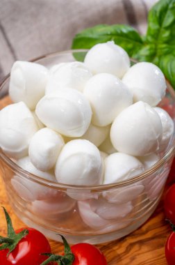 İtalyan üç renkli, küçük toplar taze İtalyan mozzarella peyniri olgun kırmızı kiraz domatesleri ve taze yeşil fesleğen otu Caprese salatası yapmaya hazır, kapatın.