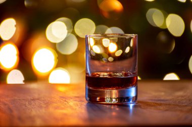 Edinburgh, İskoçya 'da arka planda parti ışıklarıyla birlikte barda servis edilen tek malt ve karışık viski bardakları