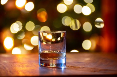 Edinburgh, İskoçya 'da arka planda parti ışıklarıyla birlikte barda servis edilen tek malt ve karışık viski bardakları