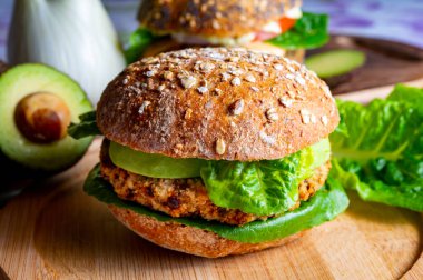 Lezzetli vejetaryen sağlıklı yeşil yemek, portakallı mercimeklerden yapılmış ev yapımı hamburgerler yeşil marul ve taze olgun avokado.