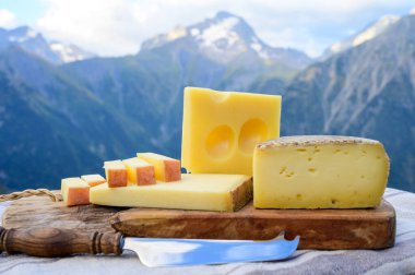 Peynir koleksiyonu, Fransız beaufort, abondance, emmental, tomme de savoie cheeses Savoy bölgesinde açık havada servis edilir, yaz aylarında Alp dağlarının zirveleri arka plandadır.