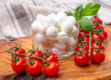 İtalyan üç renkli, küçük toplar taze İtalyan mozzarella peyniri olgun kırmızı kiraz domatesleri ve taze yeşil fesleğen otu Caprese salatası yapmaya hazır, kapatın.