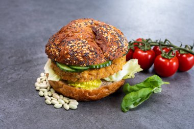 Sebze bazlı hamburgerle yapılan lezzetli vejetaryen öğle yemeği, tohumlu organik çörek ve taze sebze ve kızarmış patates.