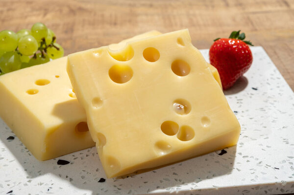 Cheese collection, blocks of French emmentaler cheese with many round holes made from cow milk close up