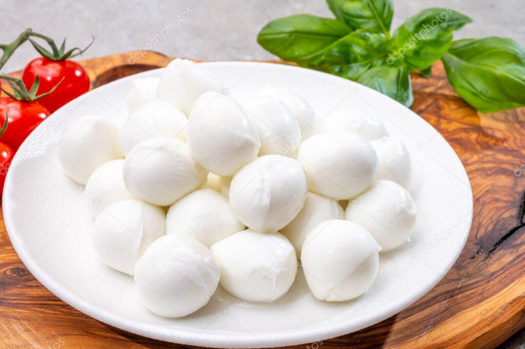 Italian tricolore, small balls of fresh white soft Italian mozzarella cheese, ripe red cherry tomatoes and fresh green basil herb, ready for making caprese salad, close up