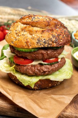Bitki bazlı soya fasulyesi burgerinden yapılmış çift katlı vejetaryen hamburgeri, tohumlu organik çörekler ve taze sebzelerle lezzetli vejetaryen yemeği hazırlıyorum.