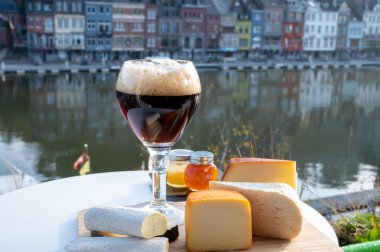 Bir bardak Belçika manastırı birası ve trapist birayla yapılan peynirleri tatmak ve Belçika, Dinant 'taki Maas nehri manzaralı güzel otlar.