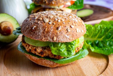 Lezzetli vejetaryen sağlıklı yeşil yemek, portakallı mercimeklerden yapılmış ev yapımı hamburgerler yeşil marul ve taze olgun avokado.