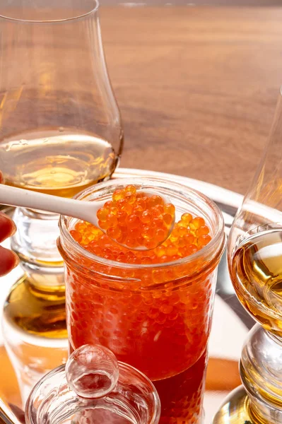 Pairing of single malt scotch or japanese whisky and high quality red trout fish caviar in glass jar