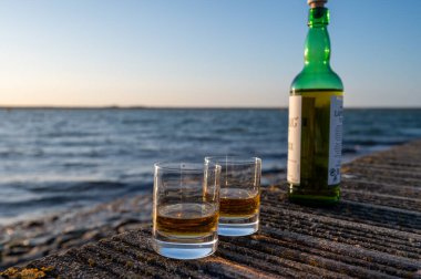 Gün batımında İskoç viskisi içmek deniz, okyanus veya nehir manzaralı, İskoçya, İngiltere 'de özel viski imalathanesi turları