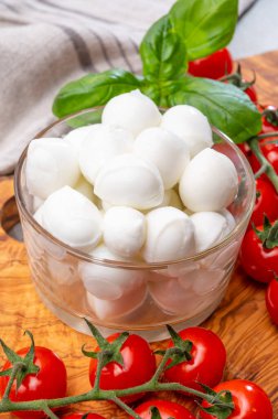 İtalyan üç renkli, küçük toplar taze İtalyan mozzarella peyniri olgun kırmızı kiraz domatesleri ve taze yeşil fesleğen otu Caprese salatası yapmaya hazır, kapatın.