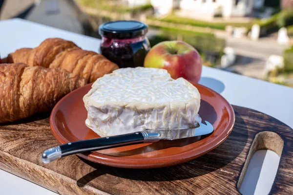 焼きたてのクロワッサンとノルマンディー産チーズを使ったフランス料理の朝食は ハート型のネフシャテルが素敵なフランスの村の景色を屋外で提供しています — ストック写真